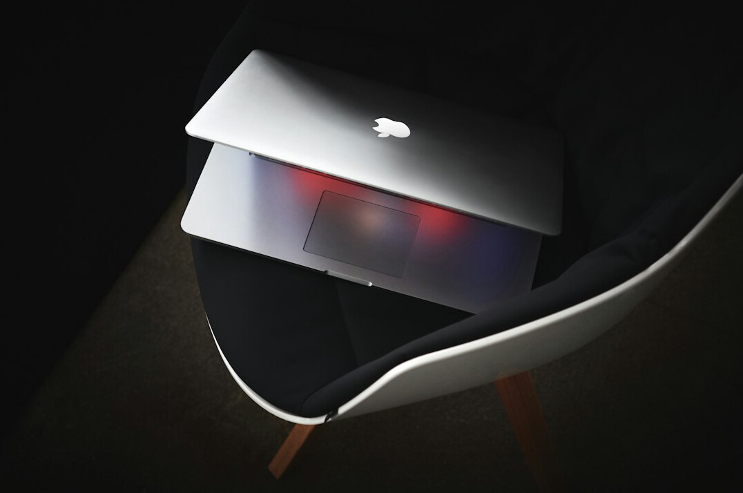 Hands typing on a laptop keyboard in a dim modern office at night
