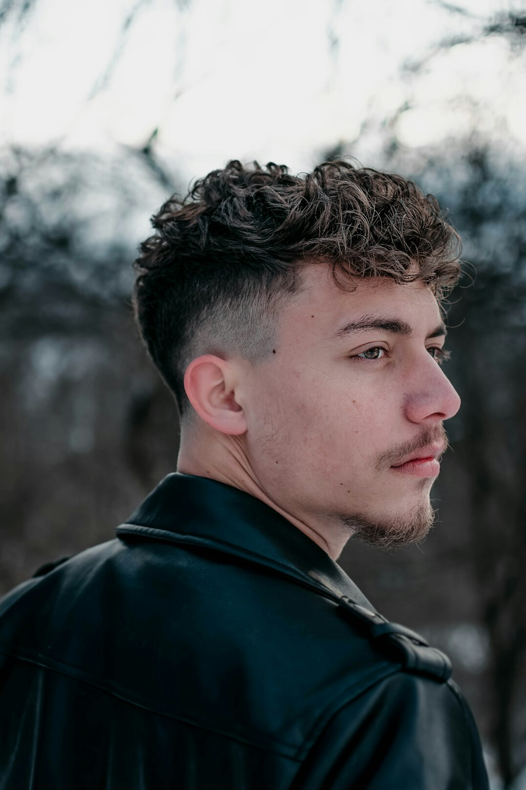 Studio portrait of a young Croatian man with curly hair smiling